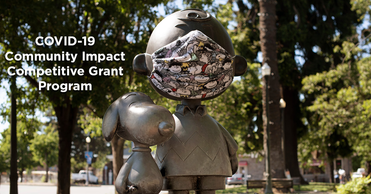Charlie Brown and Snoopy statue photographed wearing a Charlie Brown face mask. Text: COVID-19 Competitive Grants Program