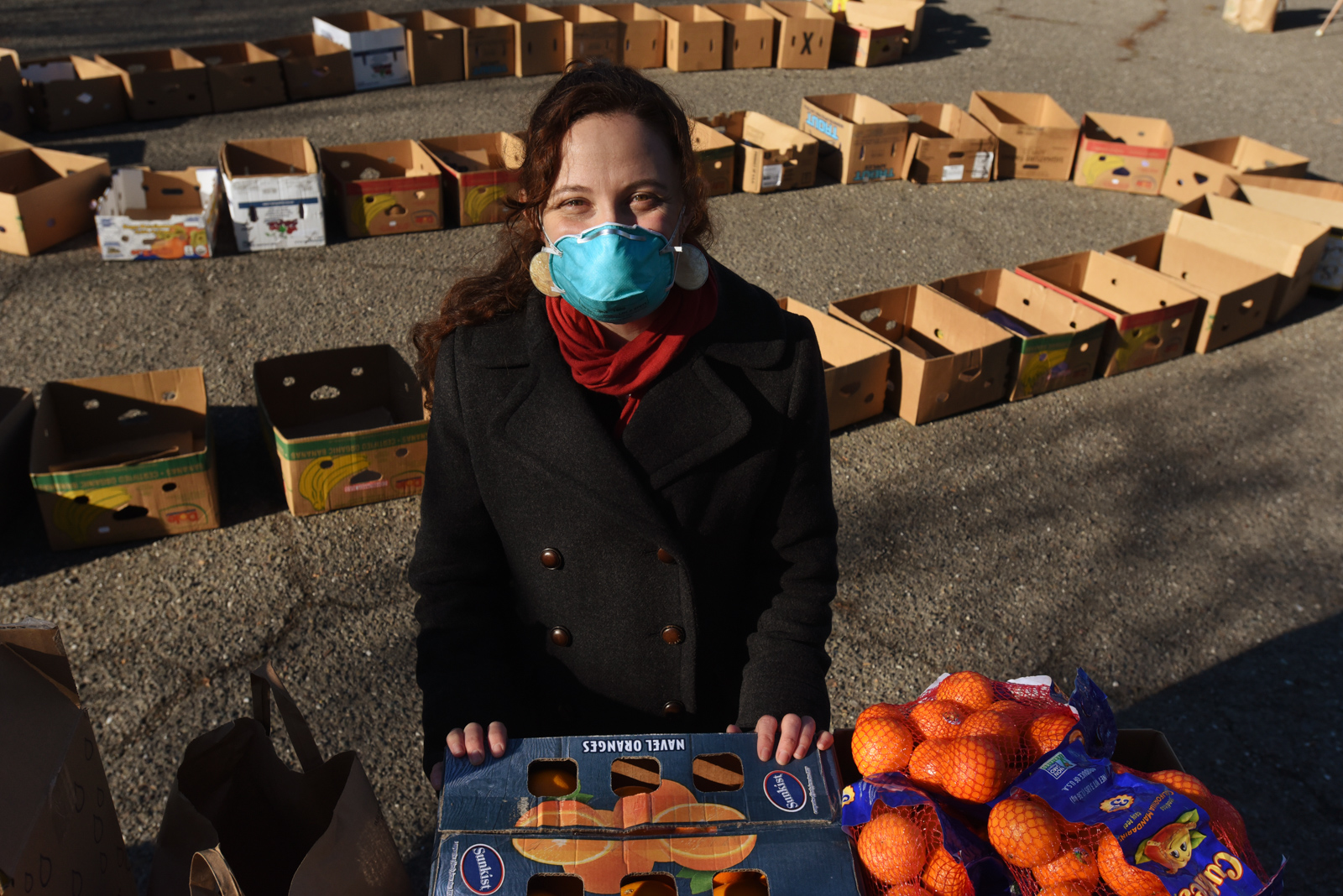 California Homemakers Association volunteer standing next to bundles of mandarin oranges.