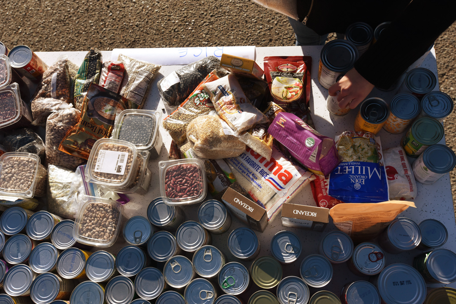 A table displaying bags of rice and beans, canned foods, and other items donated for distribution.