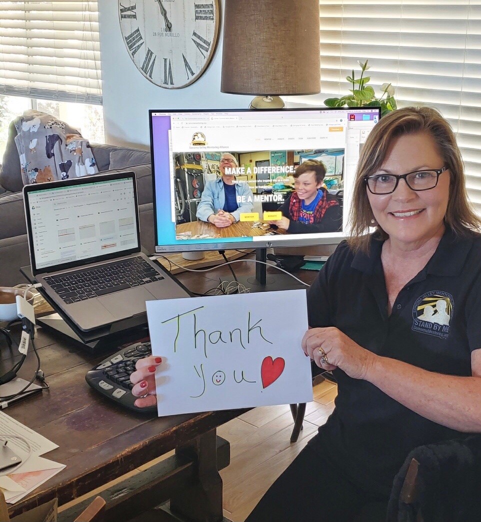 Sonoma Valley Mentoring Alliance worker holding a thank you note for receiving a grant for new laptops and training.