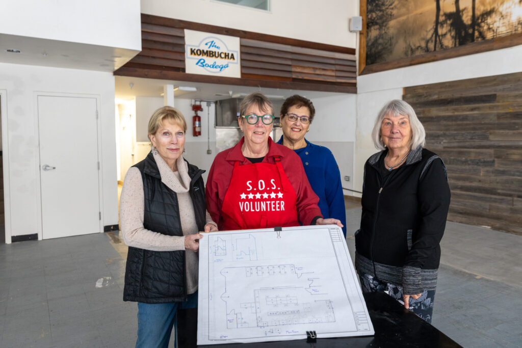 A group of board members of Sonoma Overnight Support stand holding plans for the new kitchen.