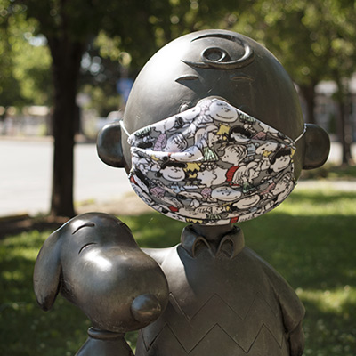 Charlie Brown and Snoopy statue photographed wearing a Charlie Brown face mask.