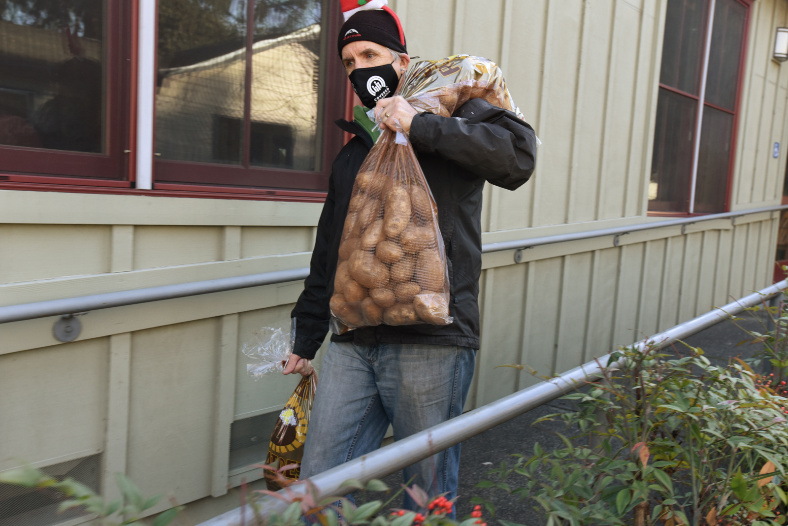 California Homemakers Association volunteer carrying three bags filled with russet potatoes.