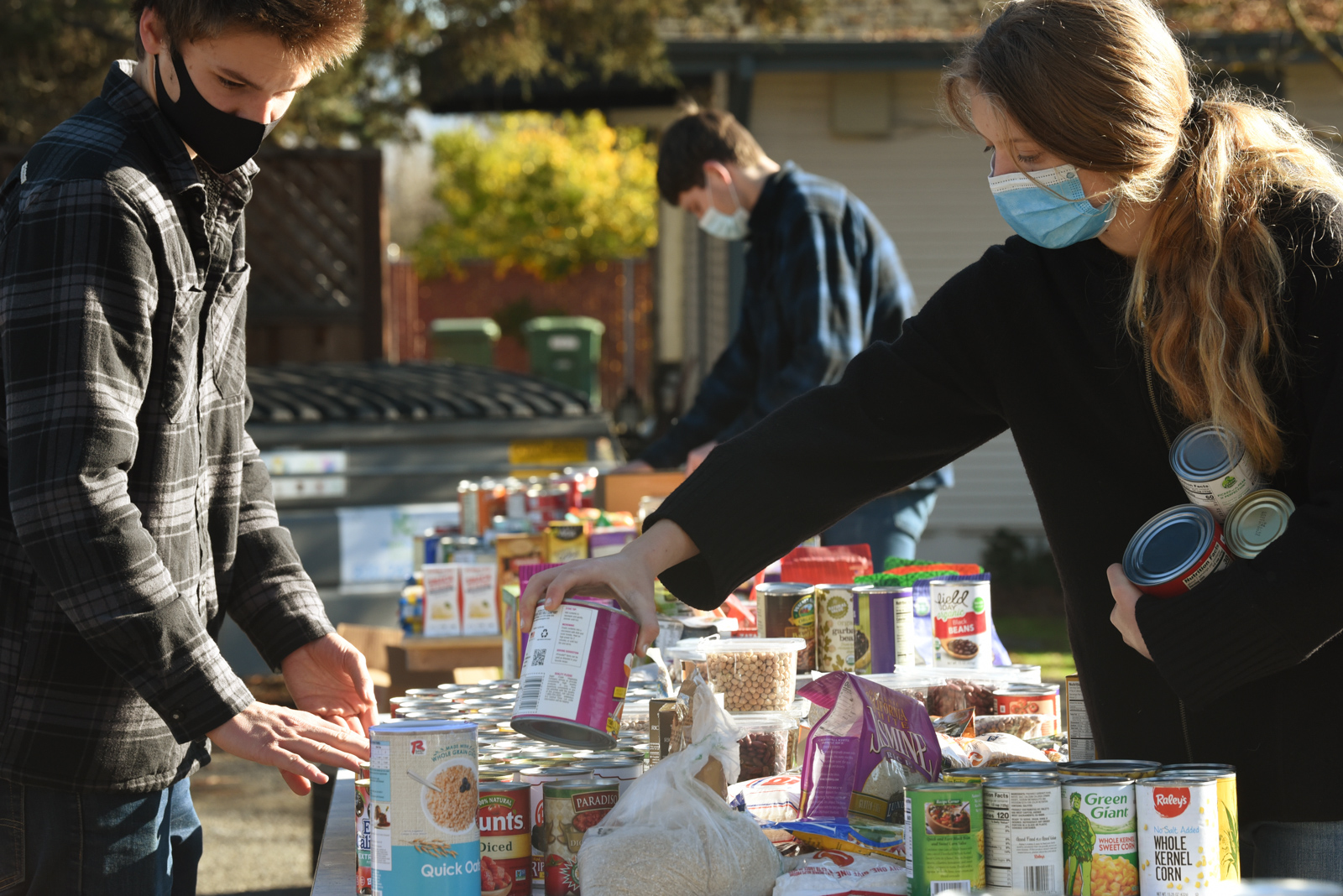 Volunteers for California Homemakers Association placing canned food items on a table.