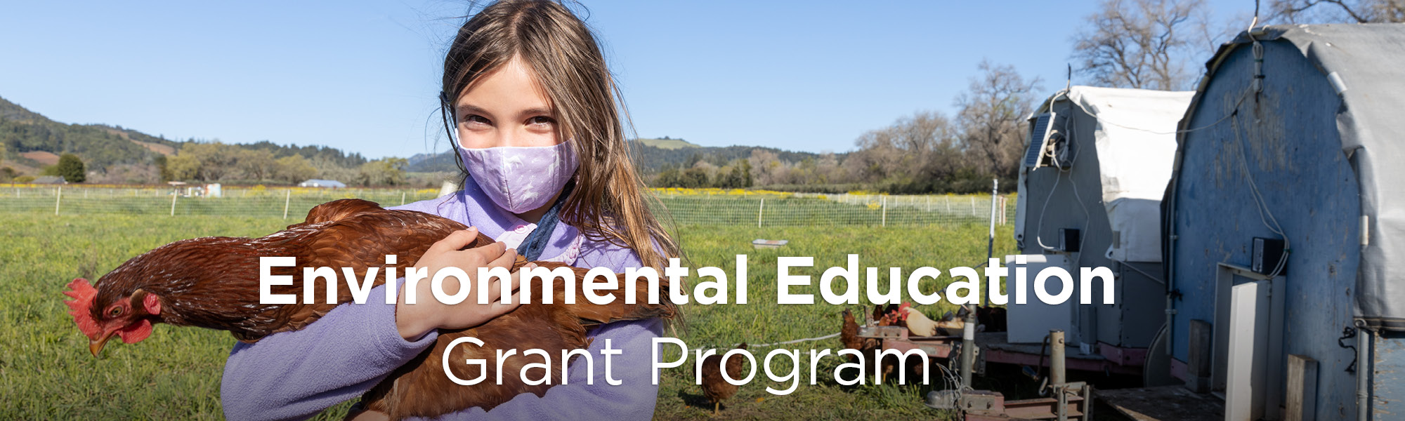 A young girl on a farm wearing a purple sweater and purple mask holding a chicken in her arms.. Text reads: Environmental Education Grant Program
