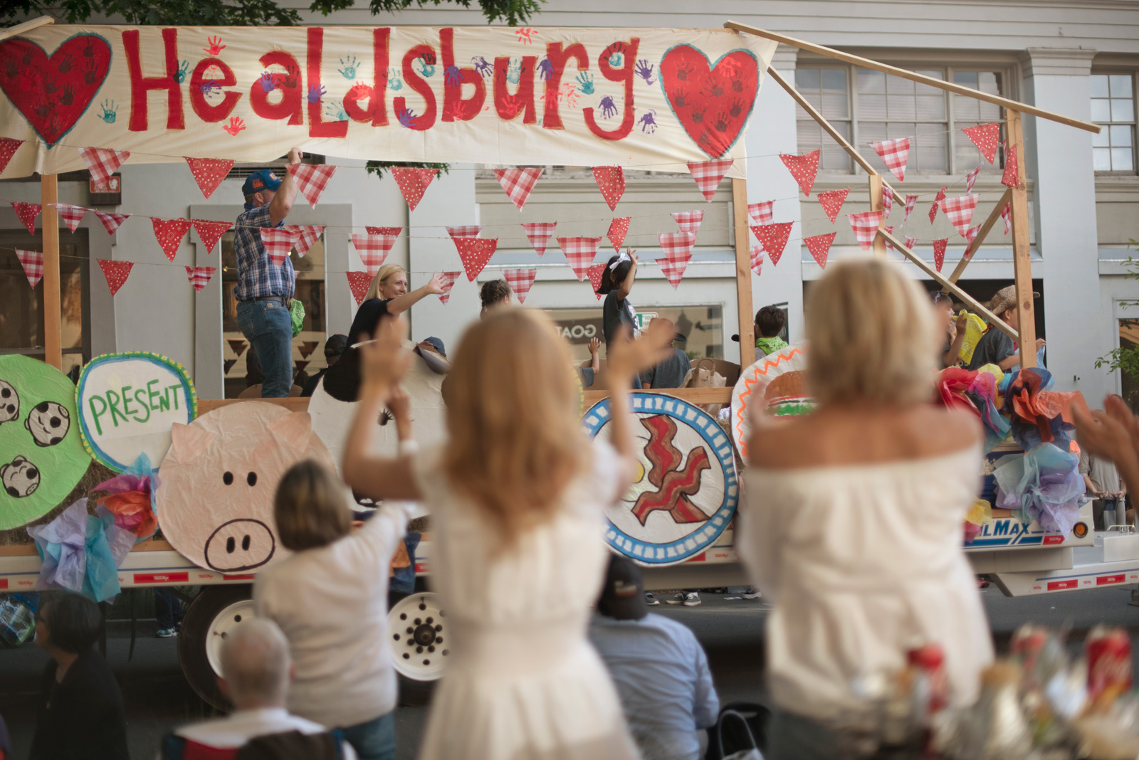 People watch a parade float with a sign reading "Healdsburg" at the Healdsburg parade.